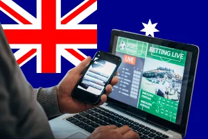 Australian gambling ads on mobile and laptop with sports betting interface and national flag background highlighting online wagering reform debate